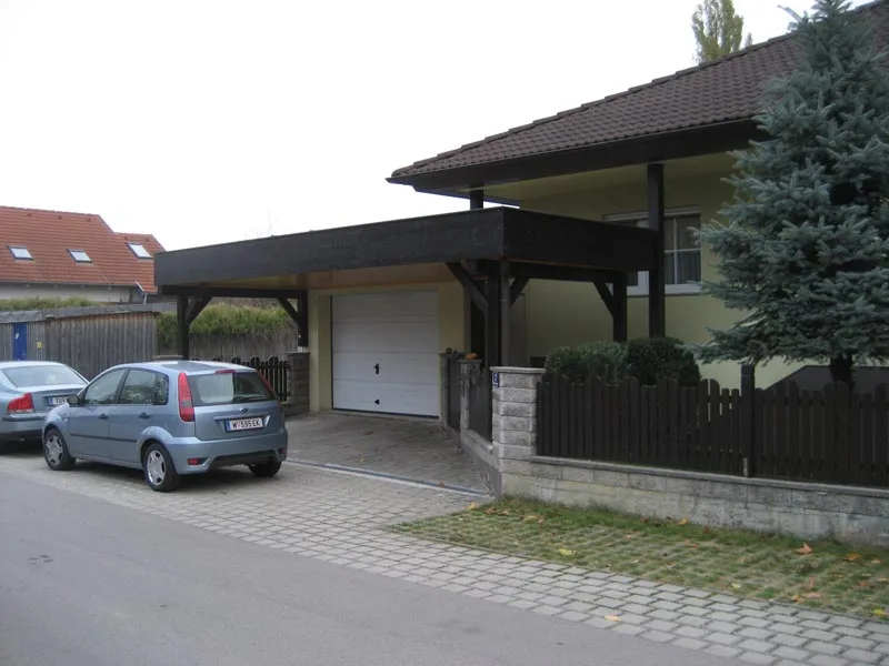 Dunkler Holzcarport vor einem Wohnhaus